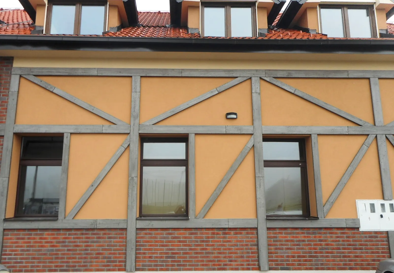 Narančasto pročelje s rasterom dekorativnih greda iznad prozora i opečne sokle