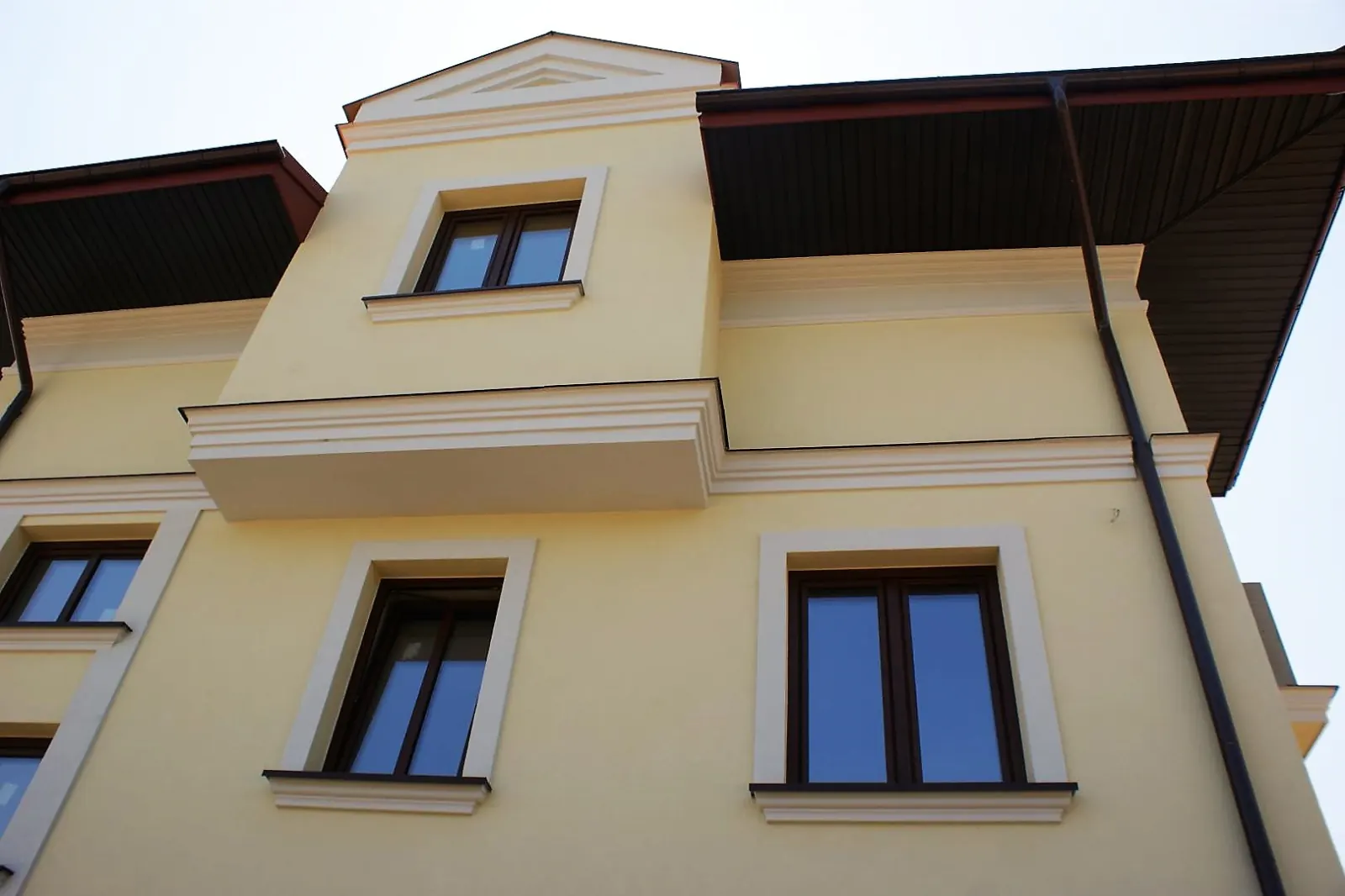 Žuto pročelje s bijelim prozorskim okvirima, katnim vijencem i krovnom profilacijom